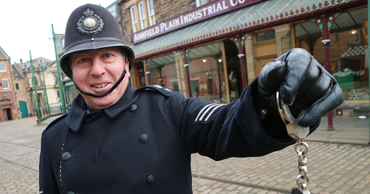 man dressed as police man holding up handcuffs at Beamish Museum